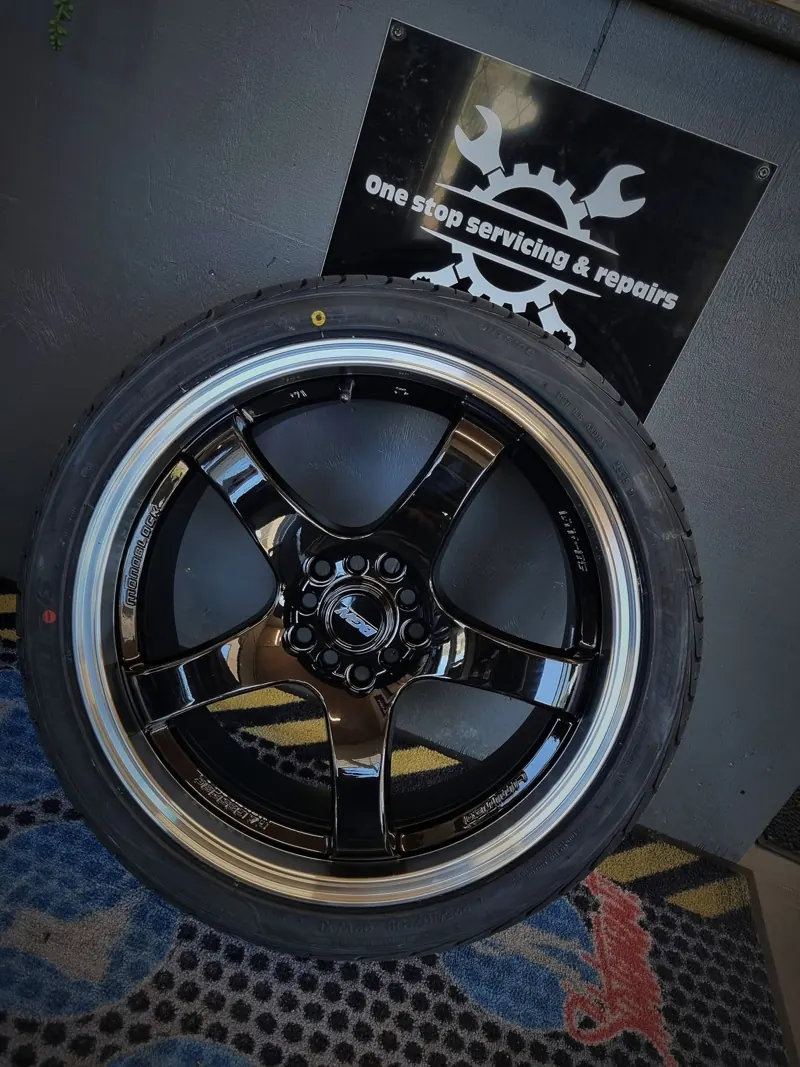 New black alloy wheel and tyre in front of a One Stop sign